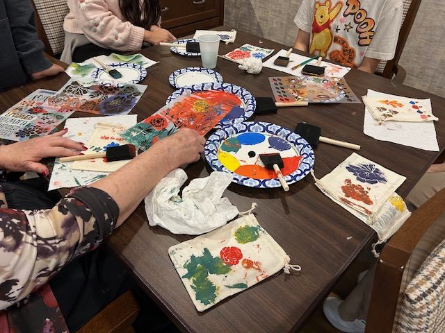 Residents and volunteers painting fabric drawstring bags together